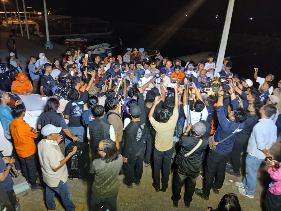 Kerumunan jurnalis dan kamera media massa sedang mewawancarai pejabat di posko pencarian darurat pada malam hari terkait kecelakaan laut wartawan hilang di Selat Sunda.