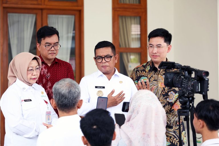 Andra Soni mengenakan kemeja putih sedang berbicara di depan wartawan dan media dalam sebuah wawancara.