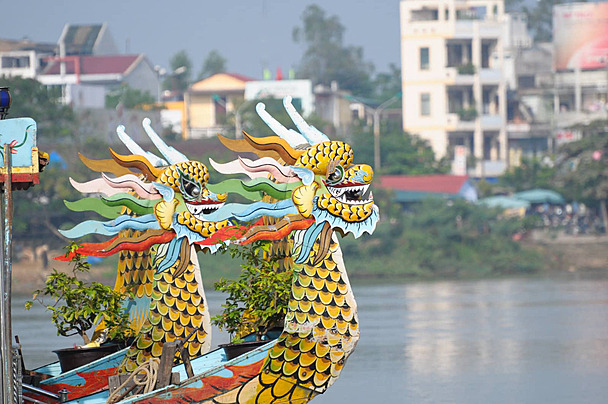 Perahu kayu tradisional dengan hiasan kepala naga berwarna-warni yang bersandar di dermaga wisata air Sungai Tahang Greenbelt PIK 2 Tangerang Banten.